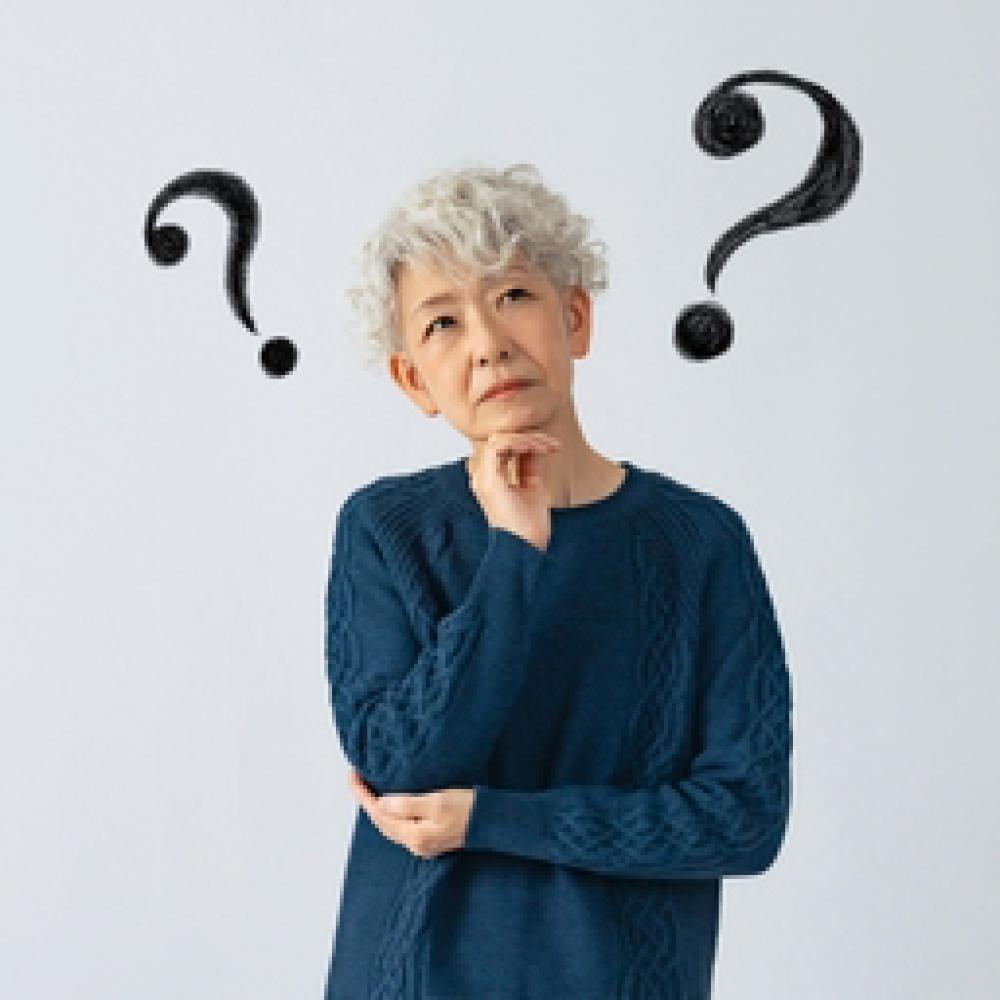 An image of an Asian senior woman pondering with two large black question marks by her head