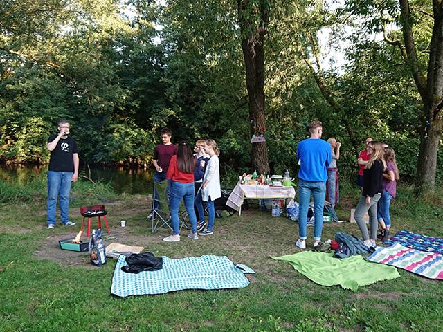 A group of 11 people having a picnic near a river
