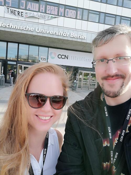 A woman wearing sunglasses and a man taking a selfie in front of a office building in Berlin